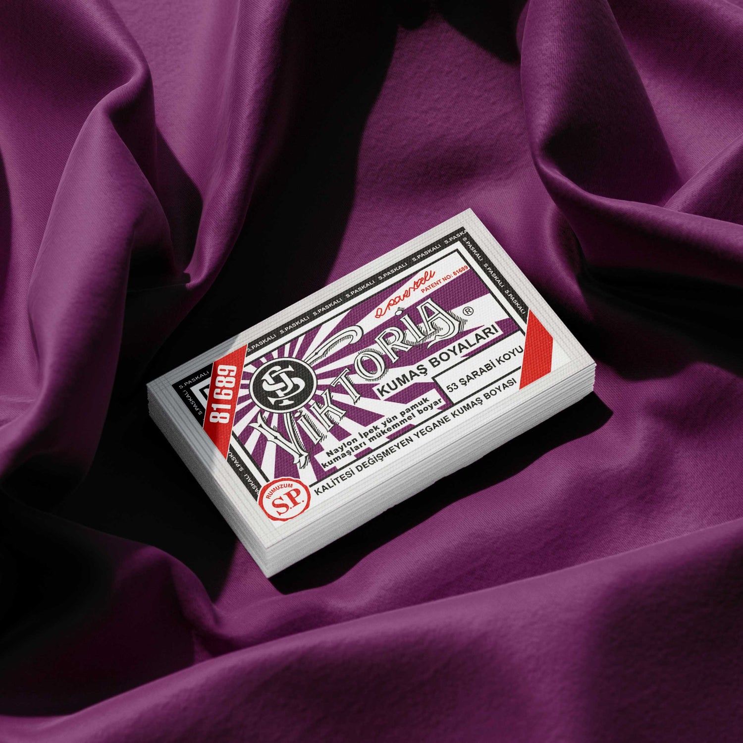 Pack of Wine Red fabric dye placed on a vibrant purple fabric background